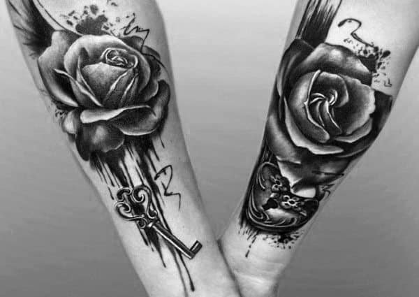Matching forearm tattoos featuring realistic roses, one with a key and the other with a heart-shaped lock, symbolizing love, passion, and a perfect connection.