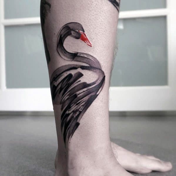 Elegant black swan tattoo on the leg with a red beak and bold brushstroke-style wings, combining minimalism with artistic flair.