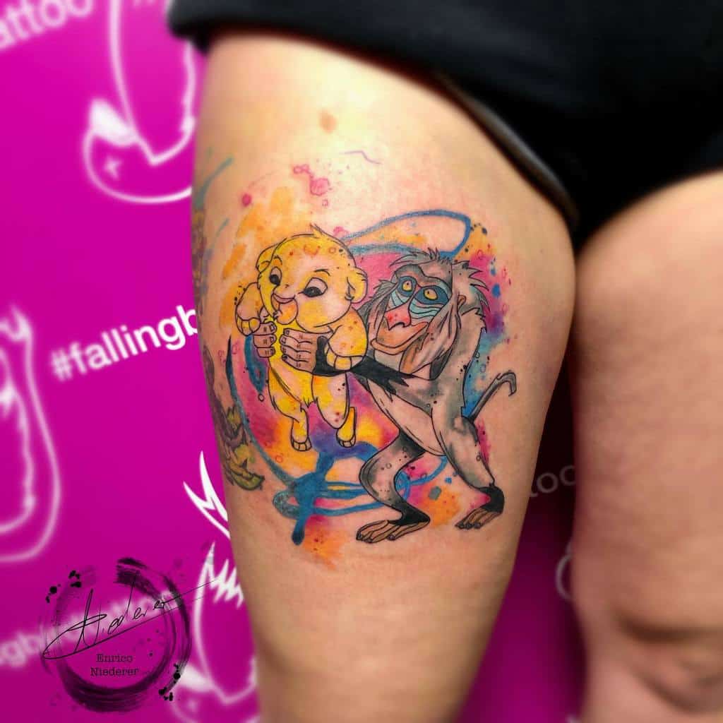 Colorful tattoo of young Simba being held by Rafiki with splashes of bright watercolor, capturing a joyful and spiritual moment from 'The Lion King.'