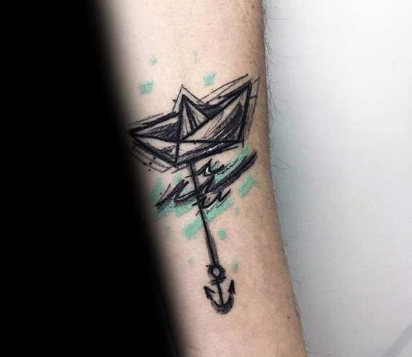 Sketch-style tattoo of a paper boat with an anchor below, accented with blue watercolor splashes, symbolizing adventure and stability.