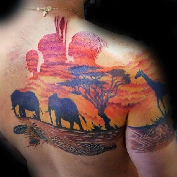 Tattoo of African safari sunset with elephants, giraffe, and a woman on a shoulder