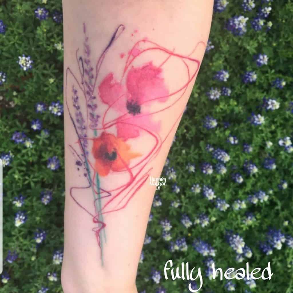 Abstract floral tattoo on forearm, surrounded by small purple flowers