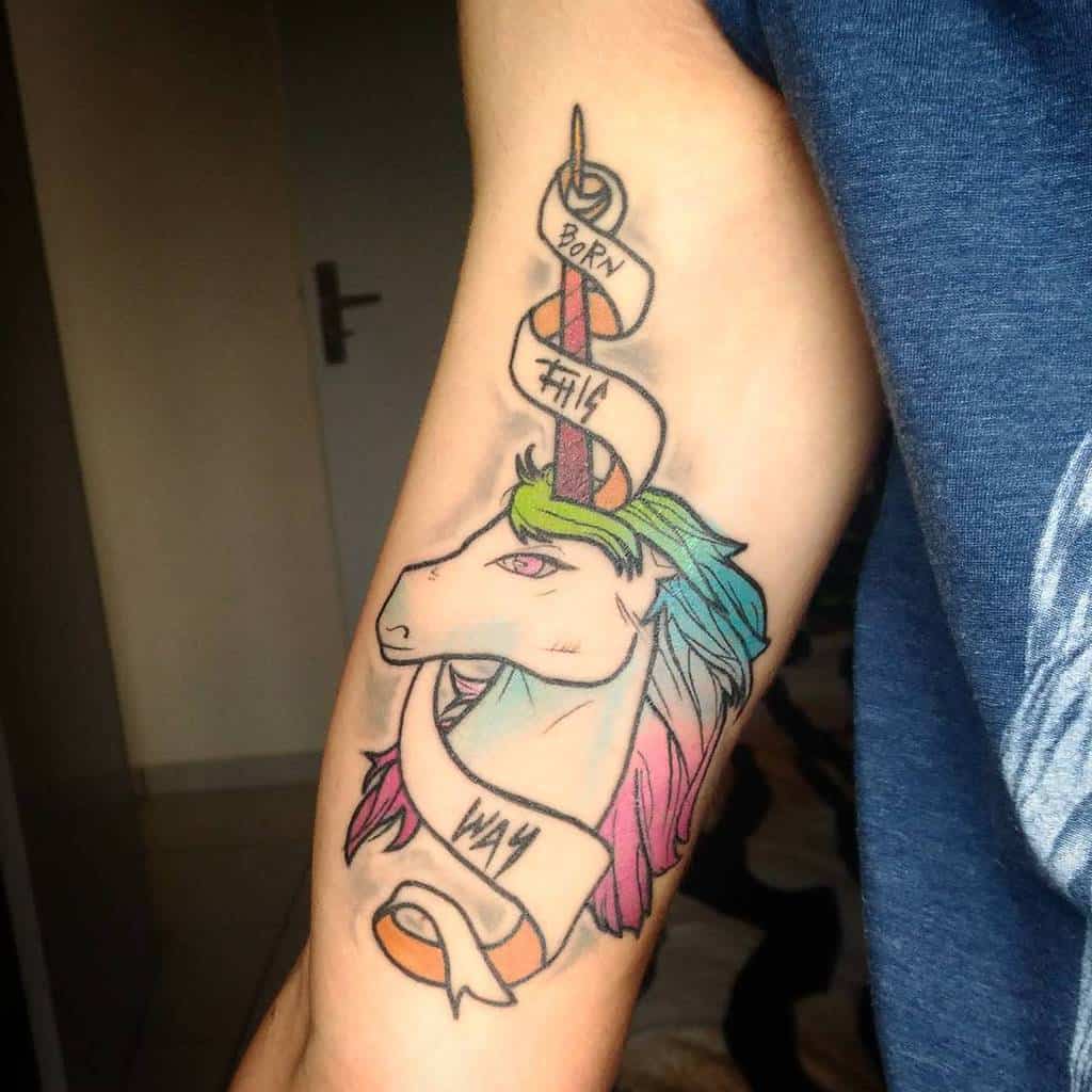 Unicorn tattoo with a rainbow mane and a ribbon saying "Born This Way" on an arm