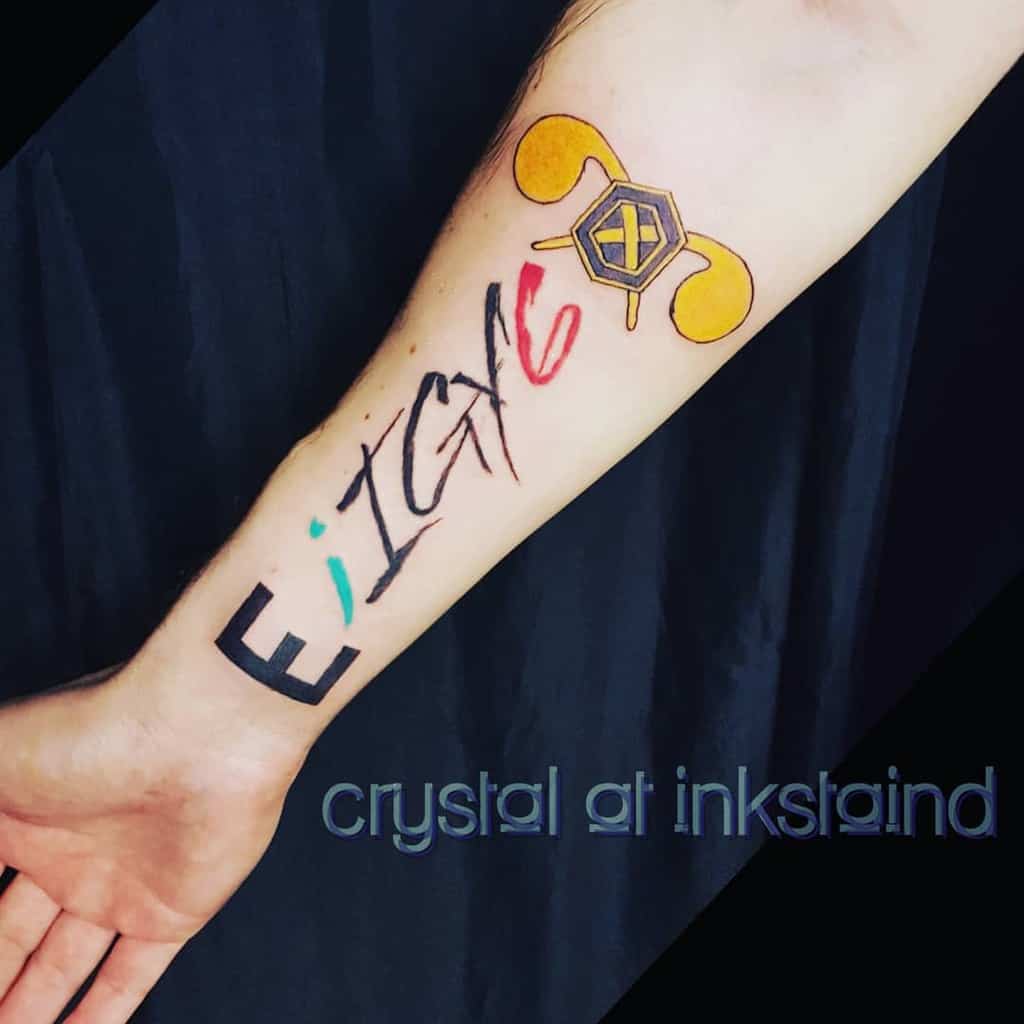 Forearm tattoo featuring 'IGY6' in bold and brushstroke styles, a blue semicolon, red 6, and a gold hexagonal design