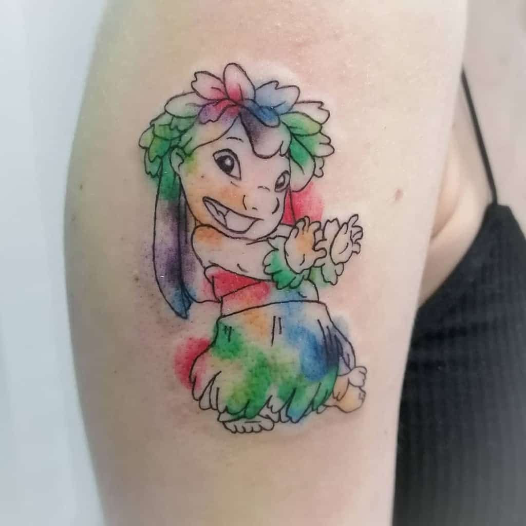 Colorful tattoo of Lilo from Lilo & Stitch wearing a hula skirt and flower crown, with vibrant watercolor splashes, on the upper arm.