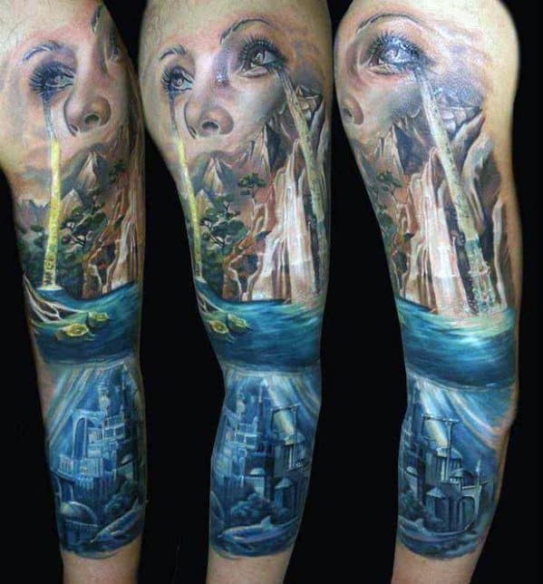 Surreal sleeve tattoo of a woman's face crying beams of light over a fantasy landscape, with a hidden underwater city below.