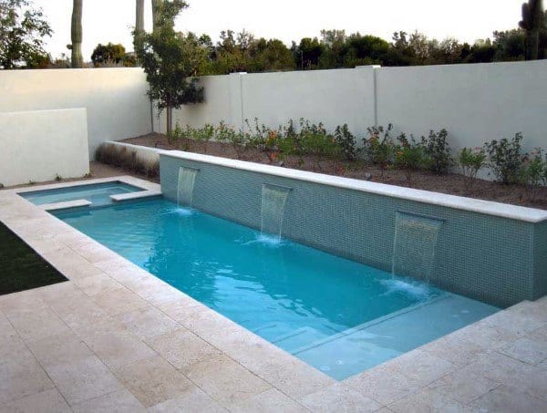 Modern pool with retaining wall waterfalls and a minimalist backyard landscape.