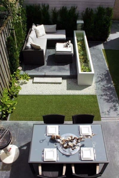 Modern backyard with outdoor seating, dining table, and a decorative planter feature.