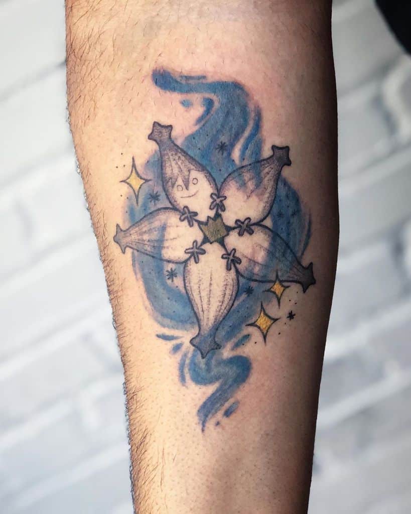 Kingdom Hearts-inspired tattoo of a Wayfinder charm with soft blue swirls and sparkles, symbolizing friendship and connection.