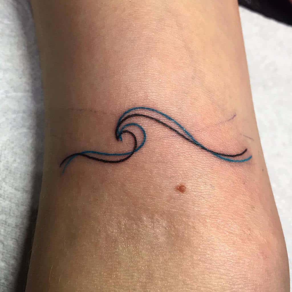 Minimalist wave tattoo, featuring a simple black and blue flowing line design for an elegant ocean-inspired look