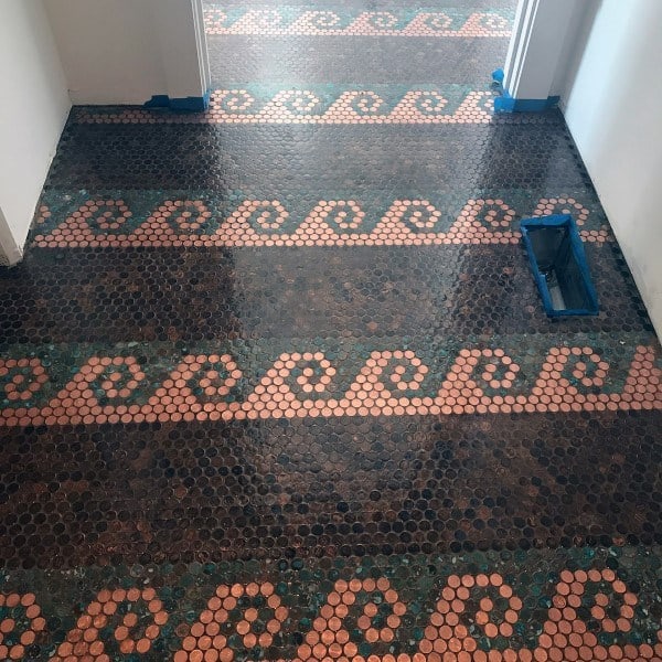 Penny tile floor with intricate wave pattern in copper and green accents for a unique design.