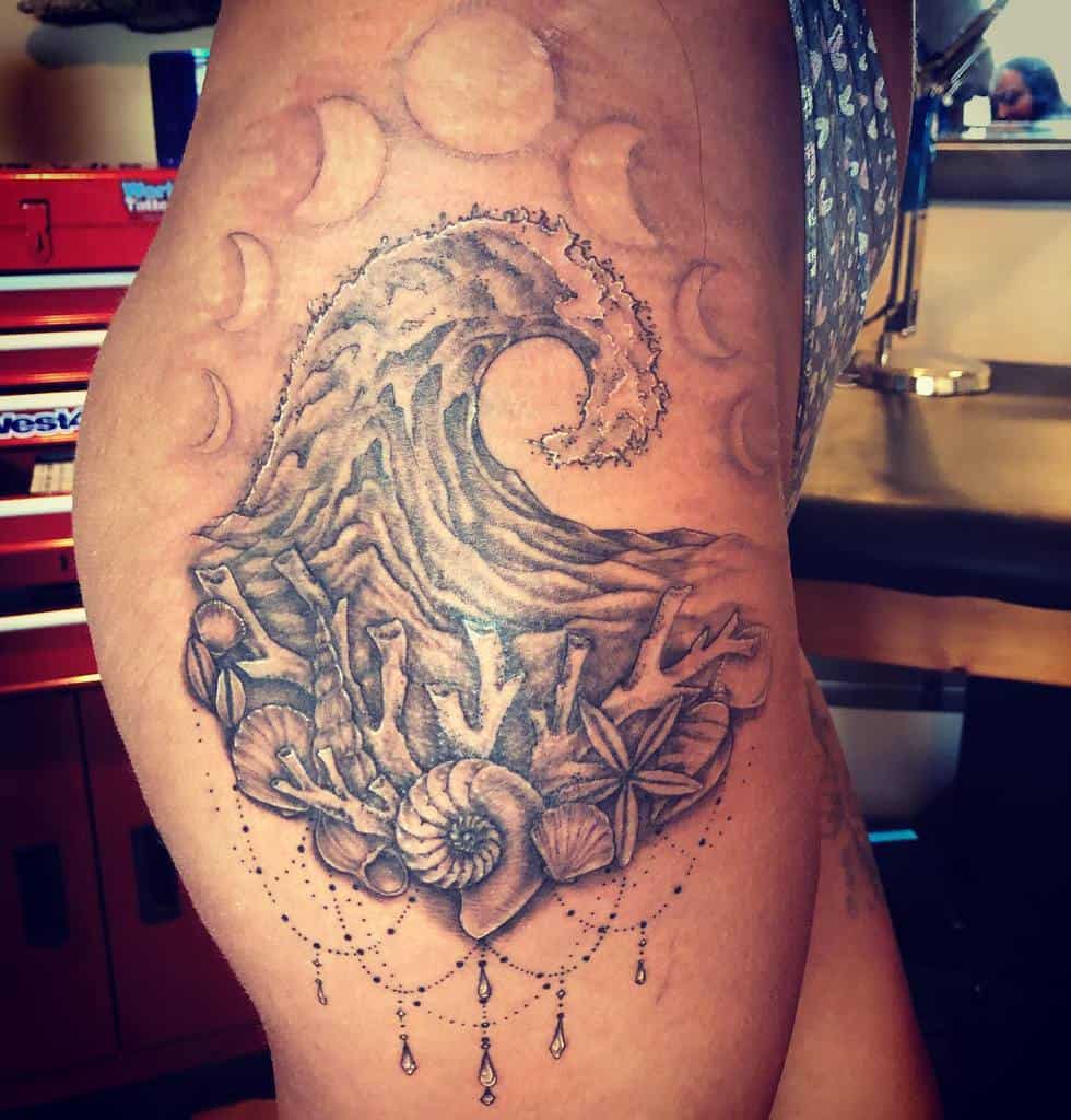 Black and grey tattoo featuring a large ocean wave, coral, seashells, and moon phases, with delicate beaded ornament details