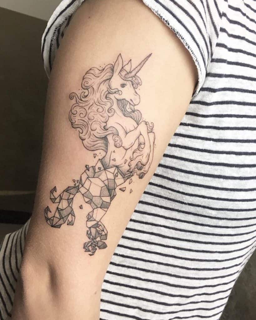 Elegant black ink tattoo of a unicorn rearing up, with a flowing mane and hind legs transforming into geometric shards for a mystical effect.