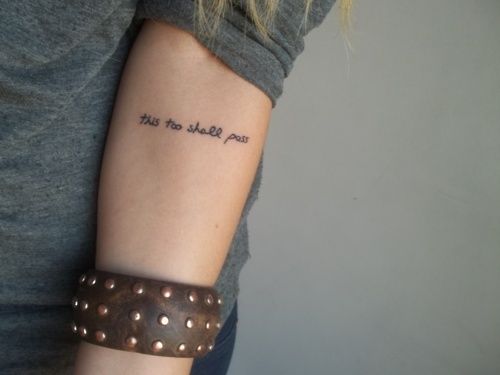 "This too shall pass" tattoo in a simple font on the forearm.
