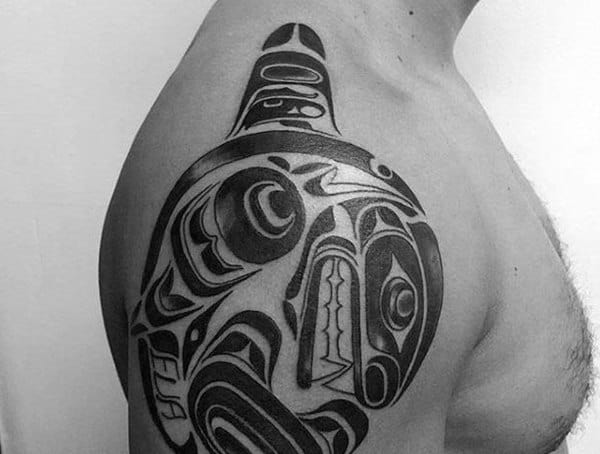 Shoulder tattoo for men featuring a bold tribal-style orca design inspired by Indigenous art in solid black ink.