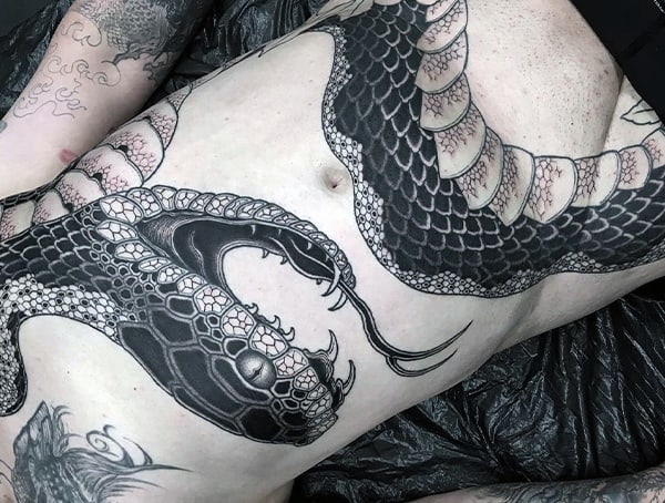 Black and white tattoo of a large snake covering a person's torso and arms