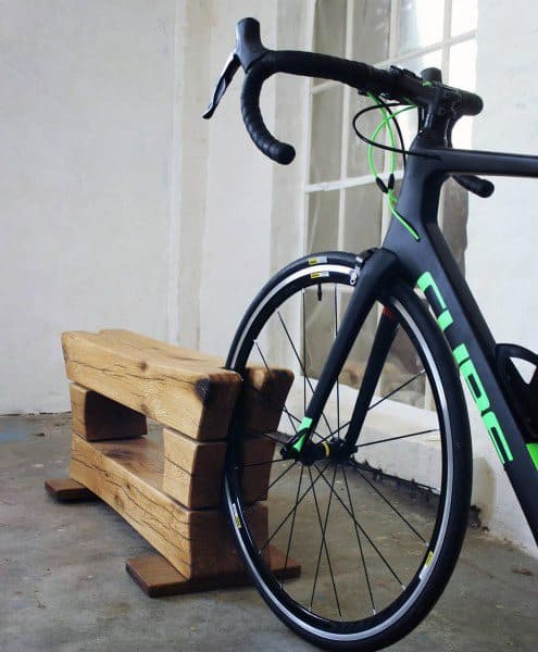 Rustic wooden wheel stand for practical and compact bicycle storage.