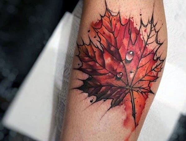 Forearm tattoo for men featuring a vibrant red maple leaf with watercolor splashes and realistic water droplets.