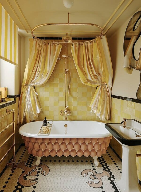 A whimsical bathroom with an egg-inspired clawfoot tub, gold fixtures, striped curtains, and bright yellow tile walls and floor.