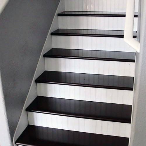Black and white painted staircase with dark wood treads and white beadboard risers.