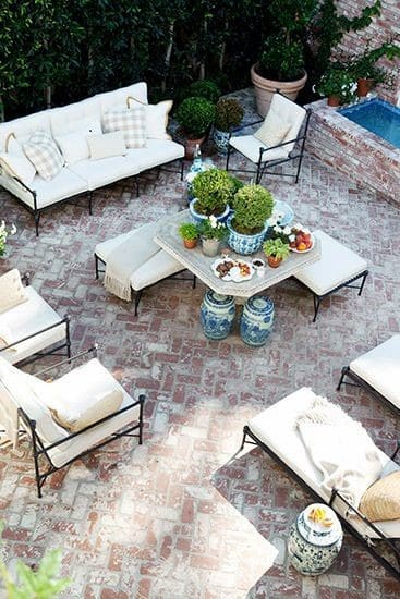 Outdoor patio with white sofas, brick flooring, and potted plants in blue and white pots