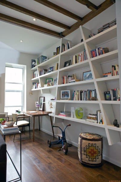 Modern study with slanted bookshelves, a wooden desk, and a window