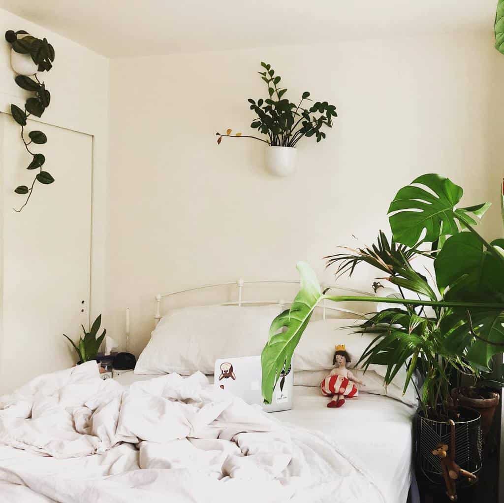 White bedroom with indoor plants and minimal decor, creating a fresh and cozy vibe.