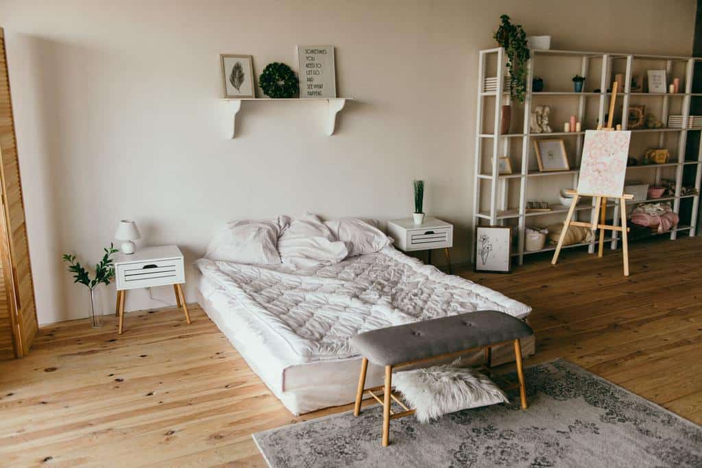 Open space bedroom with minimalist decor, wooden floors, and a cozy bed setup.