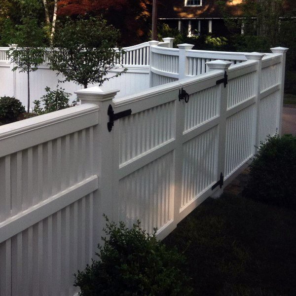 White vinyl privacy fence with decorative posts and a gate featuring black hardware.