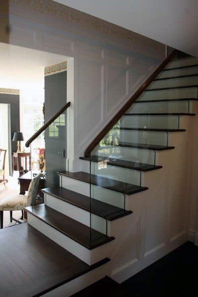 A modern staircase with dark wood steps and sleek glass railing in a well-lit, stylishly decorated room