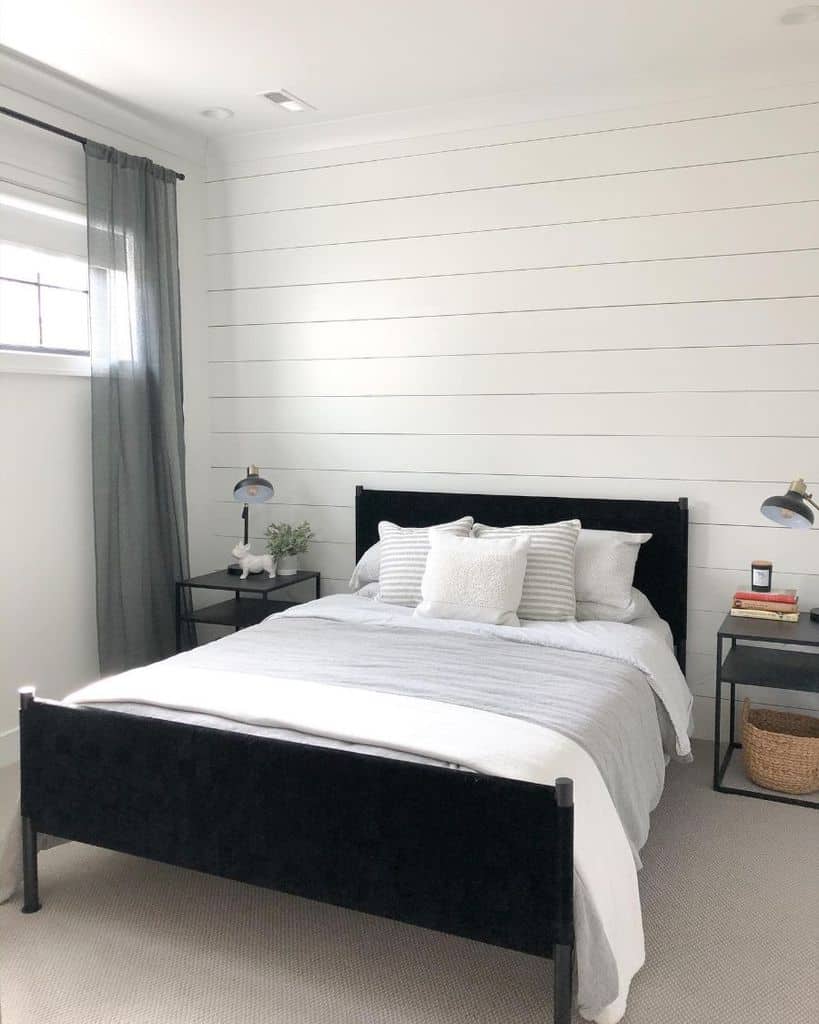 Minimalist white basement bedroom with shiplap walls, black bed frame, and simple decor.