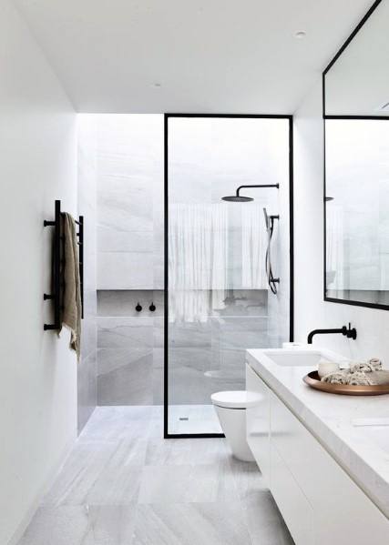 Minimalist bathroom with black fixtures, glass shower, and sleek white vanity