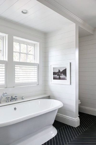 Minimalist bathroom with a white bathtub, shiplap walls, and bright natural light