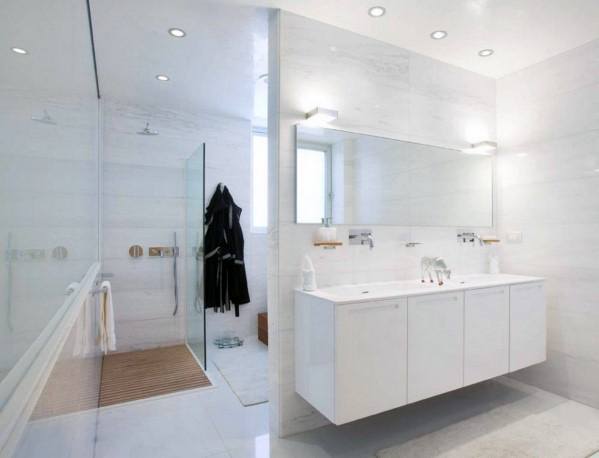 Minimalist bathroom with white glass shower, vanity mirror, and modern lighting