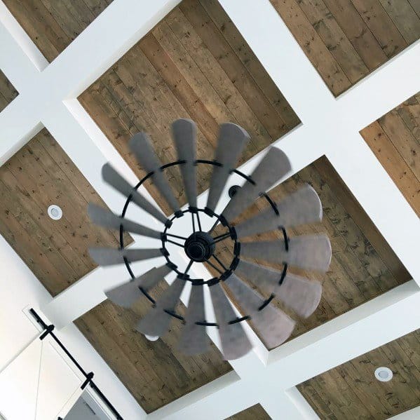 Coffered ceiling with white beams, rustic wood panels, and a windmill-style ceiling fan.