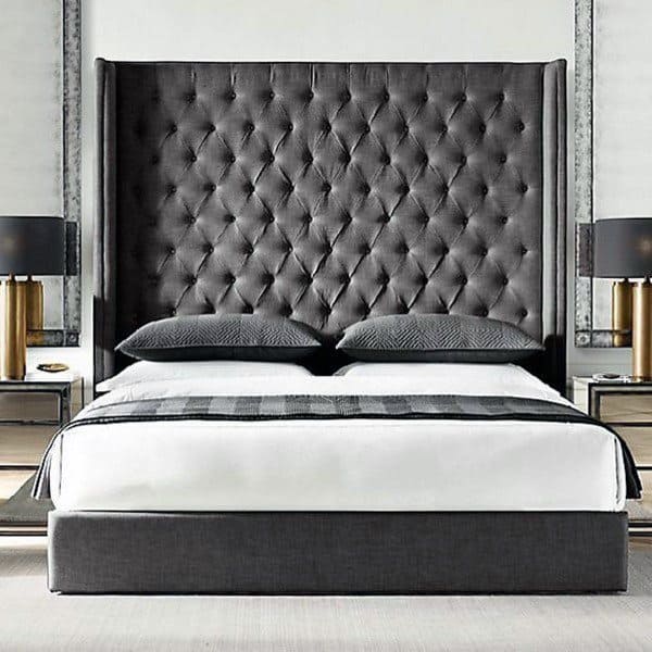 Elegant bedroom with a tall, tufted headboard, two pillows, and matching bedside tables with lamps