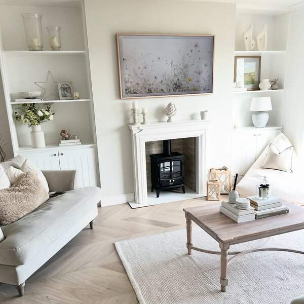 Bright living room with white built-in shelves, a cozy fireplace, and soft neutral decor.