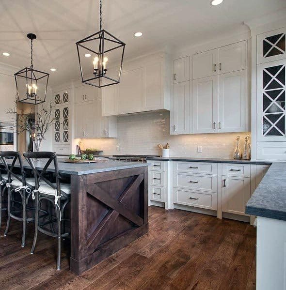 White kitchen with dark wood island, pendant lighting, and black bar stools.