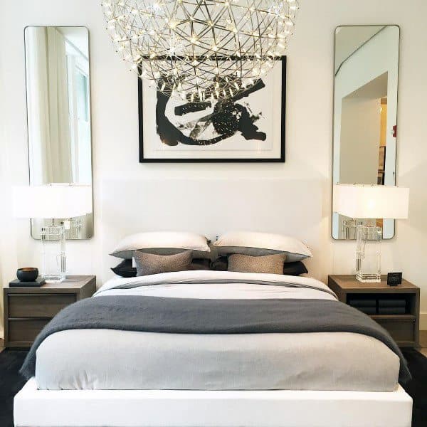 Modern bedroom with orb chandelier twin mirrors and monochrome bedding.