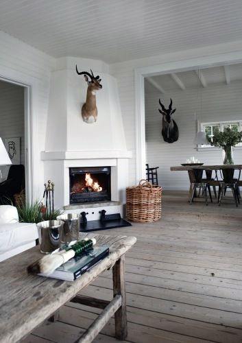 White corner fireplace with a mounted deer head, wooden floors, and rustic living room decor.