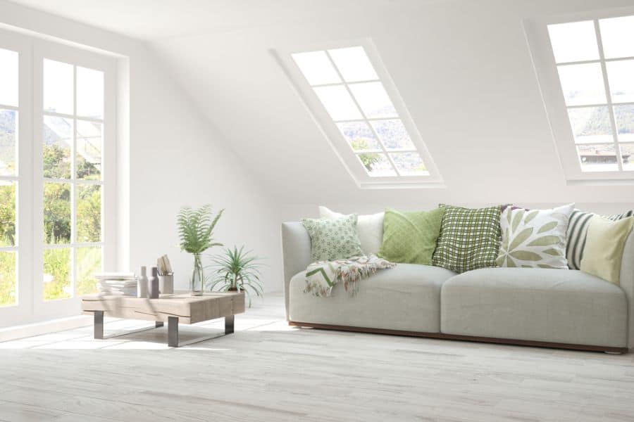 white attic living room gray couch green pillows small wood table skylights
