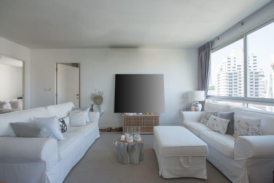 simple apartment living room white couches ottoman tv