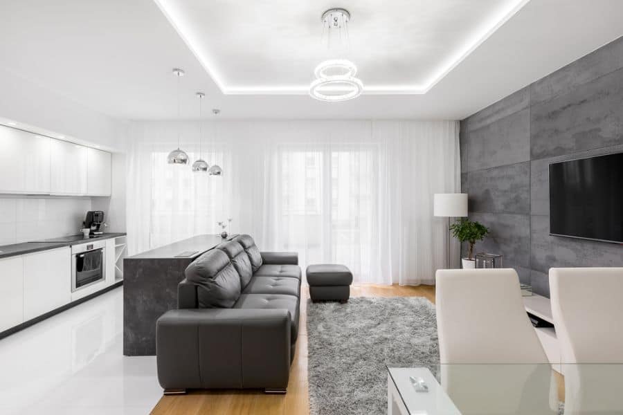 modern living room kitchen black couch marble island counter gray feature wall mounted tv