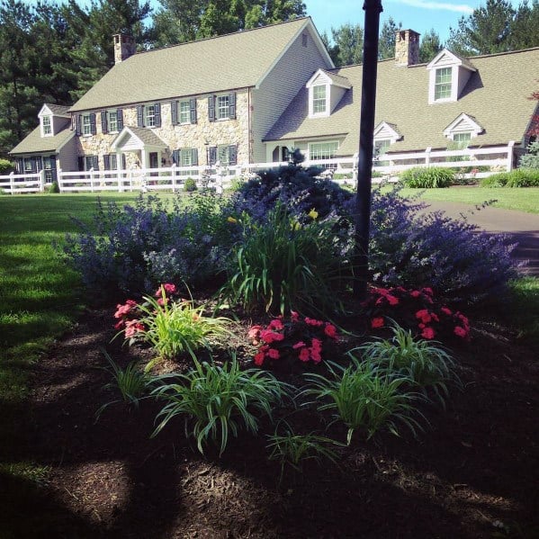 white fence front yard large house small flower garden 