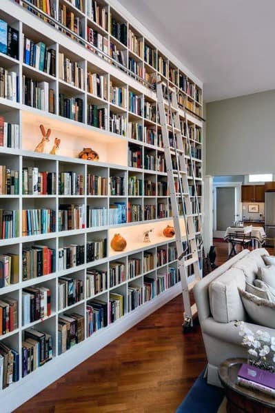 Bookshelf with ladder in cozy living room, filled with books and decorations