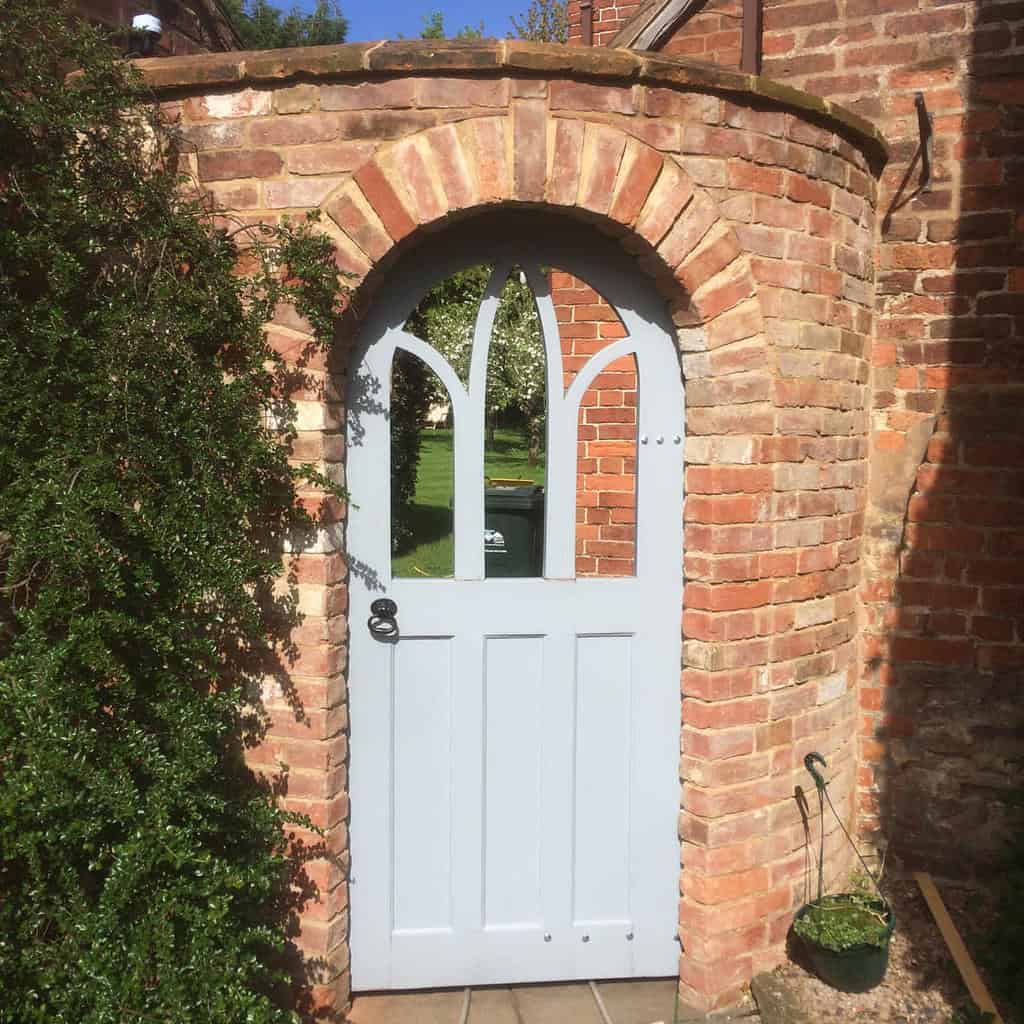 white garden gate brick wall climbing vines