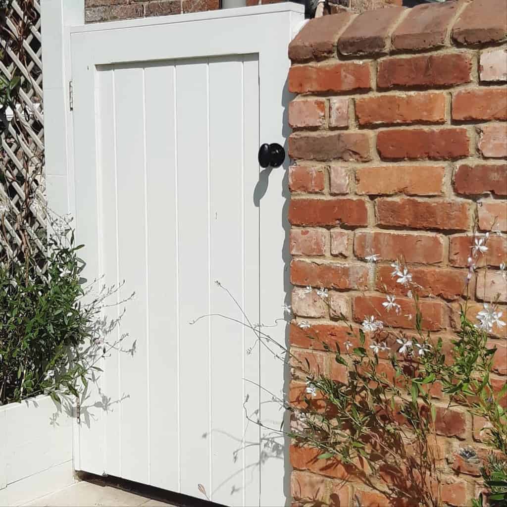 white garden gate brick wall