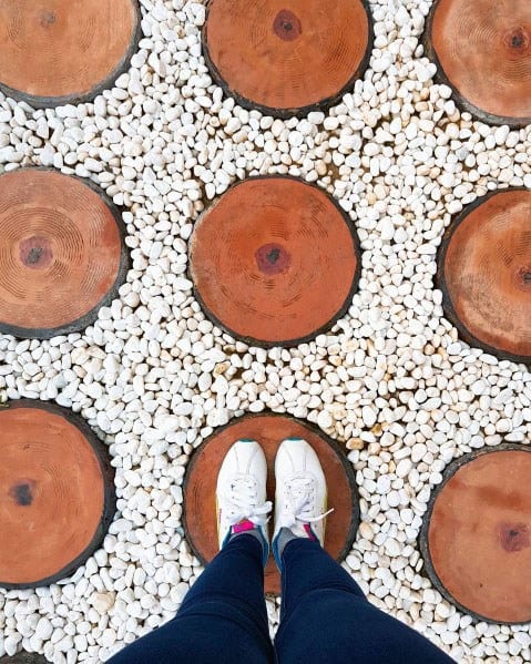 Sneakers on a walkway with round wooden steps surrounded by small white pebbles