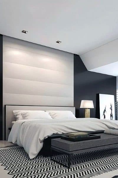 Modern bedroom with a white headboard and navy accent wall.