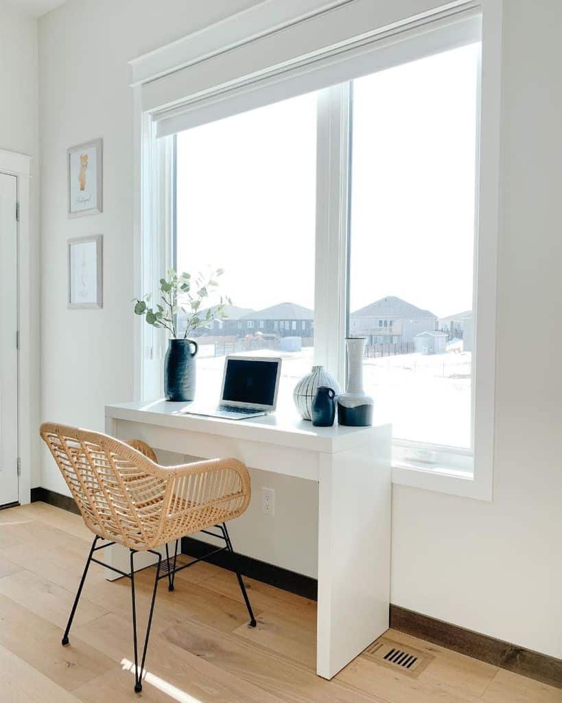 white home office simple desk wicker chair black vase window view 